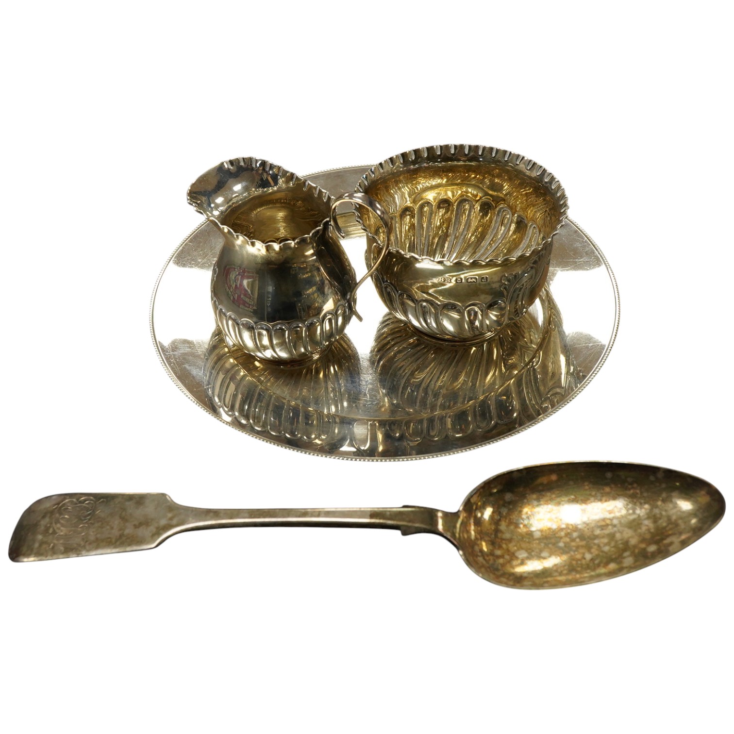 A Victorian silver side plate or stand, by John Edward Bingham (Walker & Hall), Sheffield, 1885, diameter 17.9cm, together with an early 20th century silver cream jug and sugar bowl by Barker Brothers and a Victorian pro